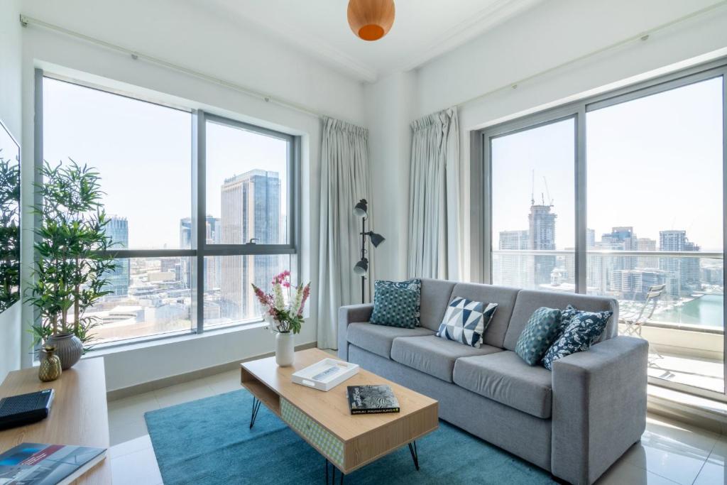 a living room with a couch and large windows at The Smart Concierge - Bay Central in Dubai