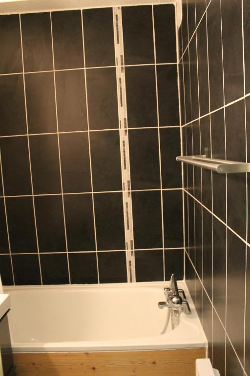 a bathroom with black tiled walls and a bath tub at L'Enclave in Les Contamines-Montjoie