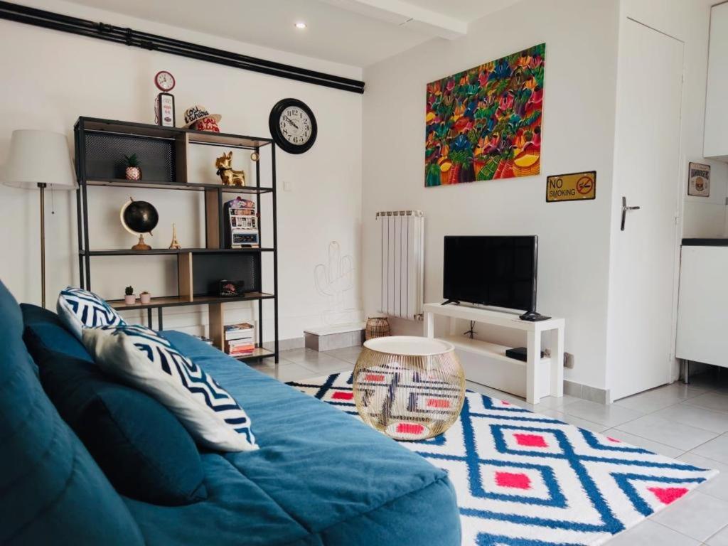 a living room with a blue couch and a tv at STUDIO COSY LE Ti PARIS WIFI &amp; NETFLIX in Deuil-la-Barre