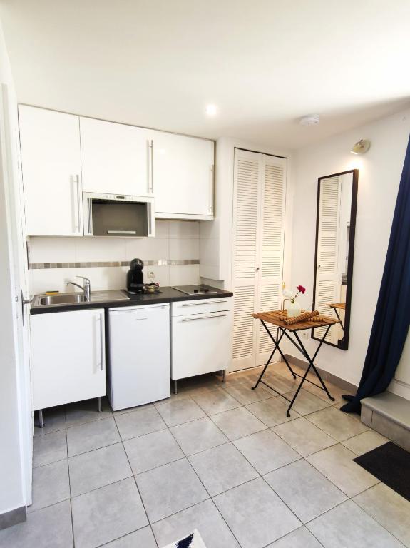 a kitchen with white cabinets and a tile floor at STUDIO COSY LE Ti PARIS WIFI &amp; NETFLIX in Deuil-la-Barre