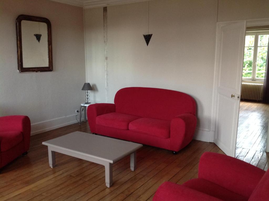 - un salon avec un canapé rouge et deux chaises dans l'établissement Appartement en centre ville, à Nevers