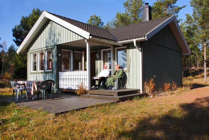two people sitting on the porch of a tiny house at Marbyfjärden seaside village Lyckan in Eckerö