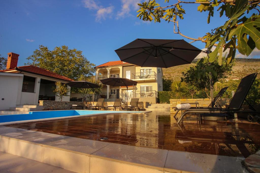 a house with a swimming pool with an umbrella at Villa Infinity Mostar in Mostar