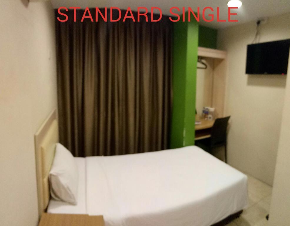 - une chambre avec un lit et un rideau vert dans l'établissement SRP Hotel Sdn Bhd, à Batu Caves