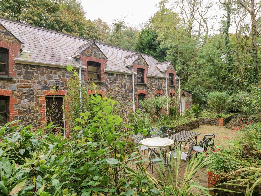 een stenen huis met een tafel en stoelen in een tuin bij The Anchorage in Haverfordwest