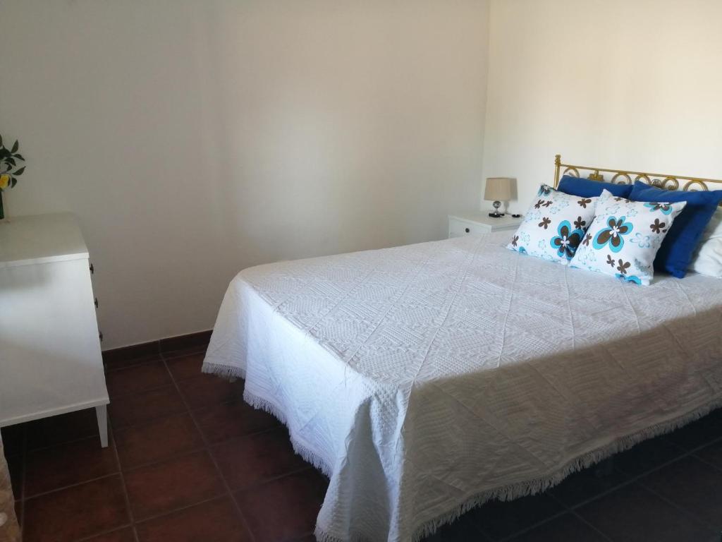 a bedroom with a white bed with blue pillows at Casas da Saibreira - nº9 in Elvas