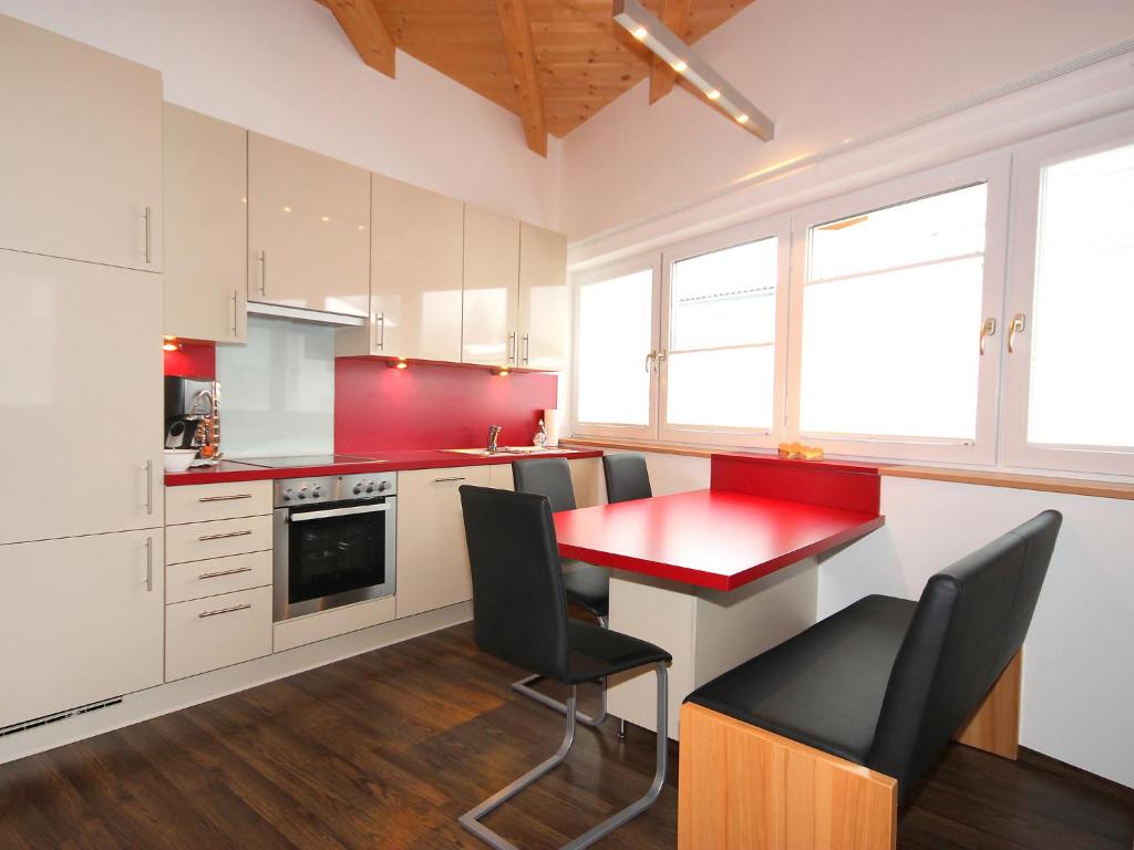 a kitchen with a red table and black chairs at Apartment Am Bärenkopf-2 by Interhome in Maurach