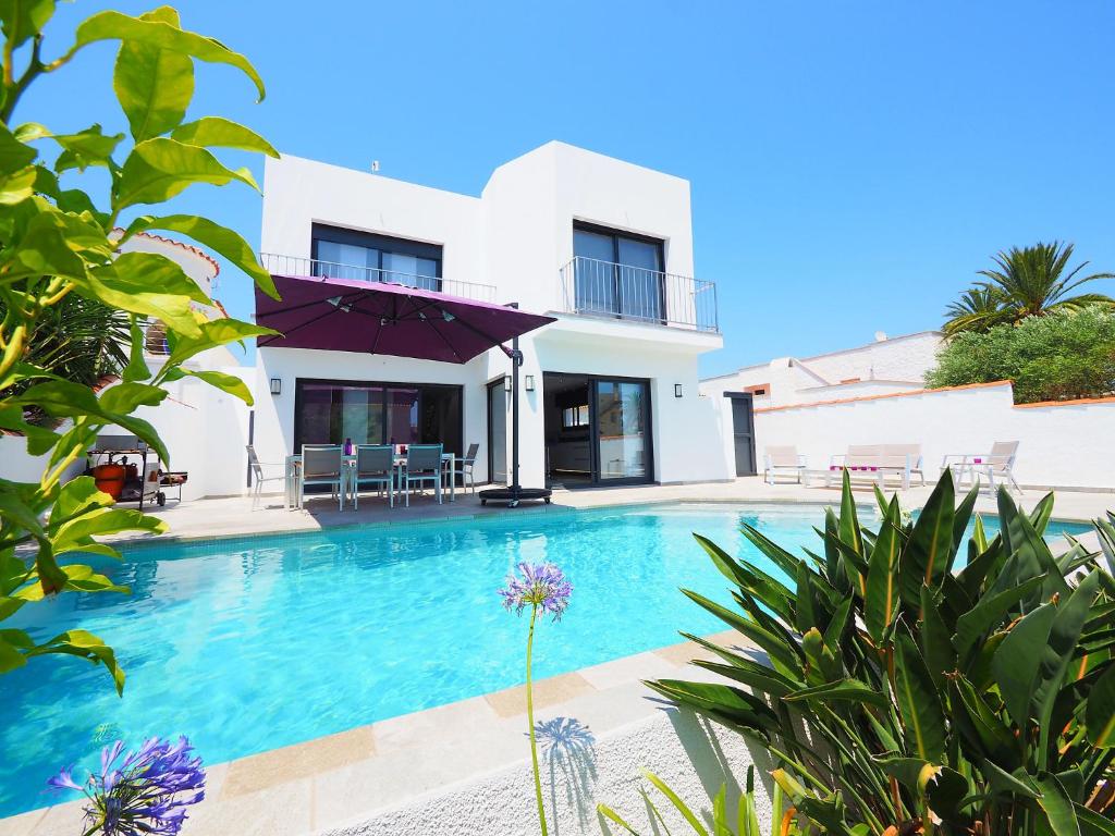 a villa with a swimming pool in front of a house at Holiday Home Norfeu by Interhome in Empuriabrava