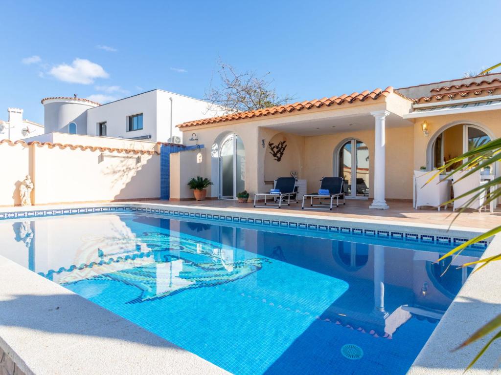 a villa with a swimming pool in front of a house at Holiday Home Bonica by Interhome in Empuriabrava
