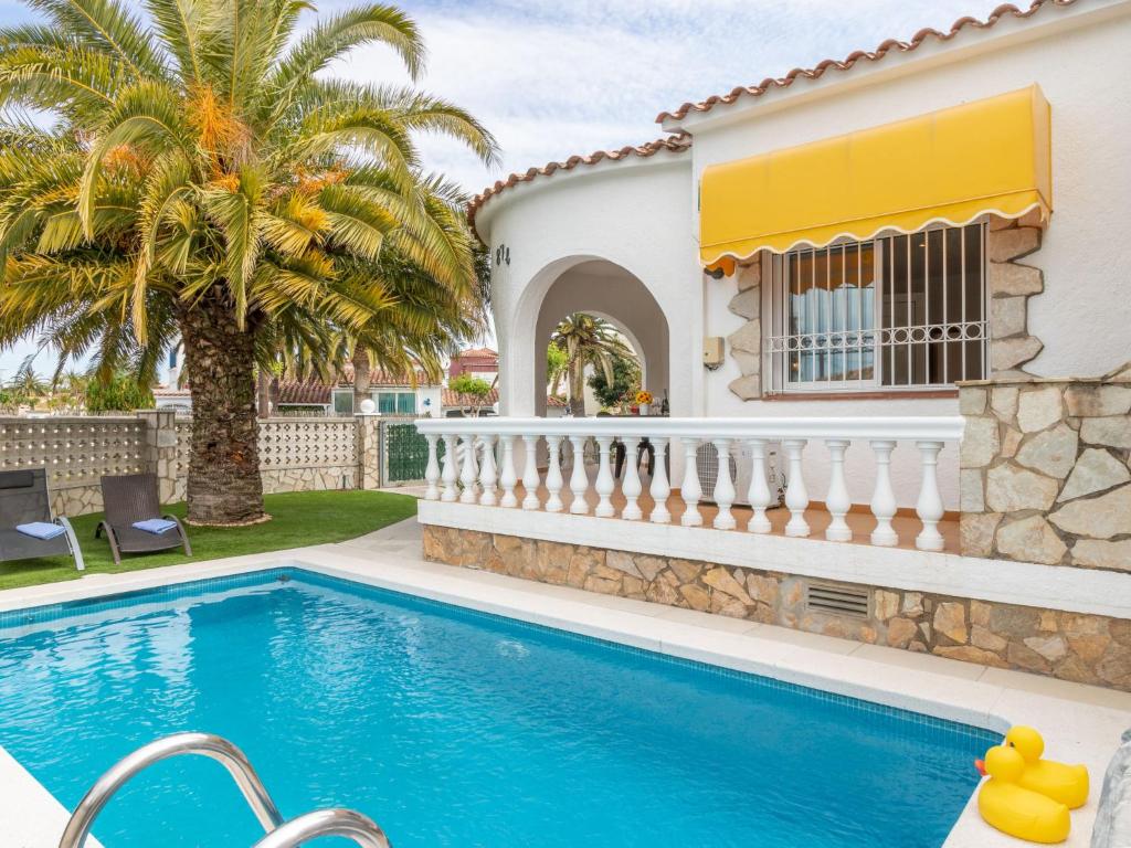 a villa with a swimming pool and a house at Holiday Home Green House by Interhome in Empuriabrava