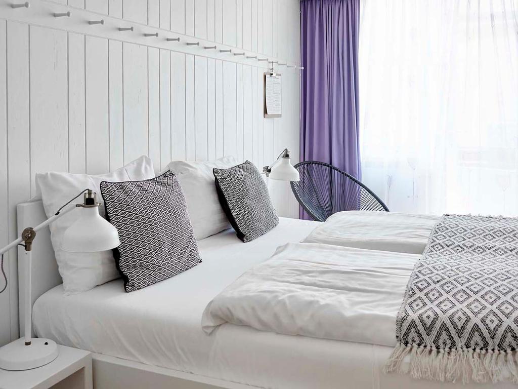 une chambre avec un lit blanc avec des oreillers et une fenêtre dans l'établissement Hotel Zonne, à Noordwijk aan Zee