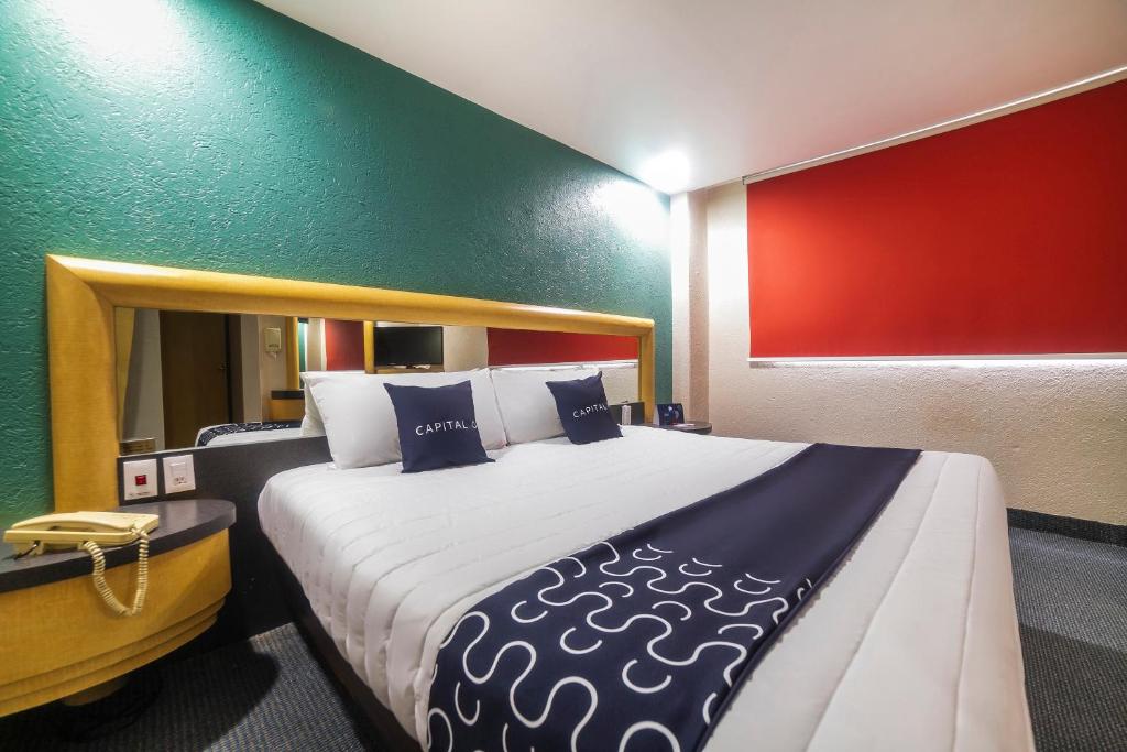 - un grand lit dans une chambre dotée d'un mur rouge et vert dans l'établissement Capital O Autoparador Del Valle,Centro Industrial Tlalnepantla, à Mexico