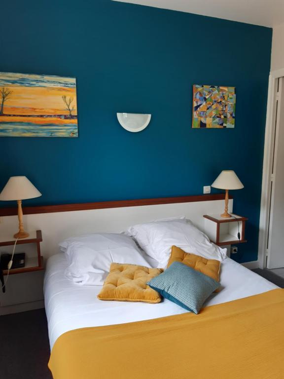 a bed in a room with a blue wall at Logis Hotel Le Relais du Serre in Dieulefit