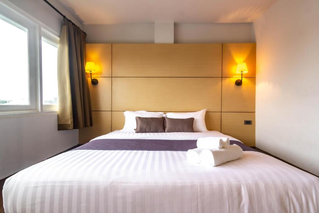 a bedroom with a large white bed with two pillows at Montree Phuket Hotel in Phuket Town