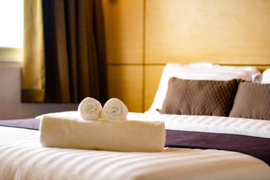 two towels on a bed in a hotel room at Montree Phuket Hotel in Phuket Town