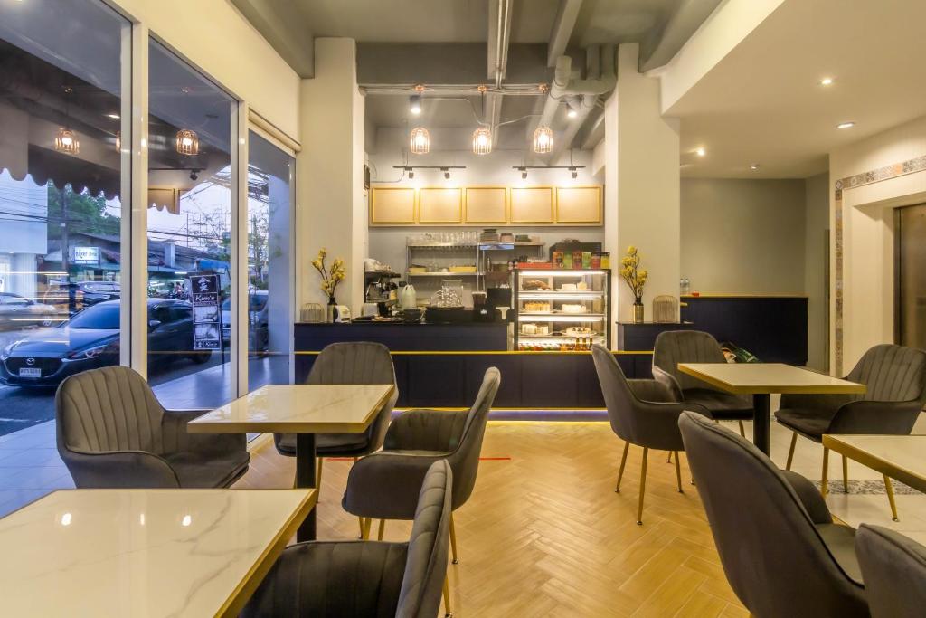 a restaurant with tables and chairs and a kitchen at Montree Phuket Hotel in Phuket Town