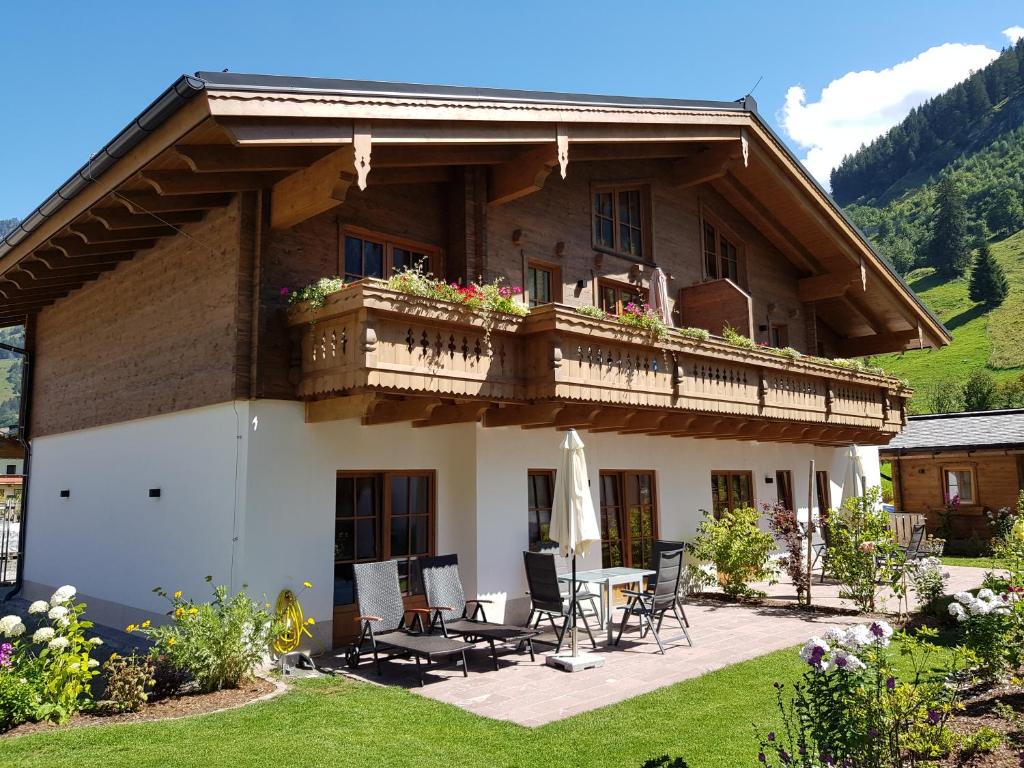 a house with a balcony and a table and chairs at Hochalmbahnen Chalets Rauris 1-05 WE1 Maislaufeldweg 1h EG in Rauris