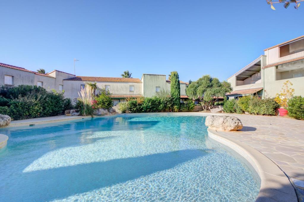 a large swimming pool with blue water in a yard at Maison d'une chambre avec piscine partagee terrasse amenagee et wifi a Valras Plage in Valras-Plage