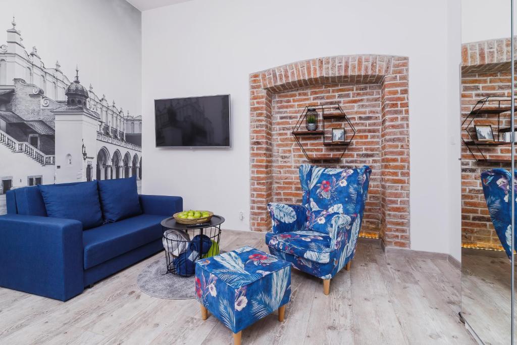 a living room with a blue couch and two chairs at Zamenhofa Studio Kraków by Renters in Krakow