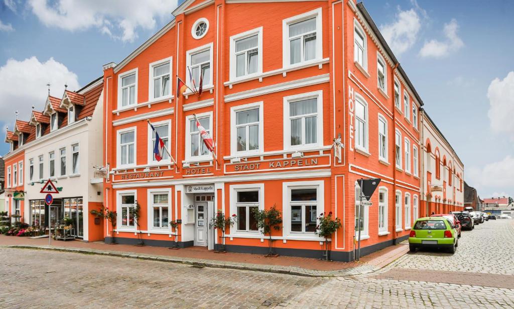 ein orangefarbenes Gebäude auf einer Straße mit einem Auto vor dem Haus in der Unterkunft Hotel Stadt Kappeln in Kappeln