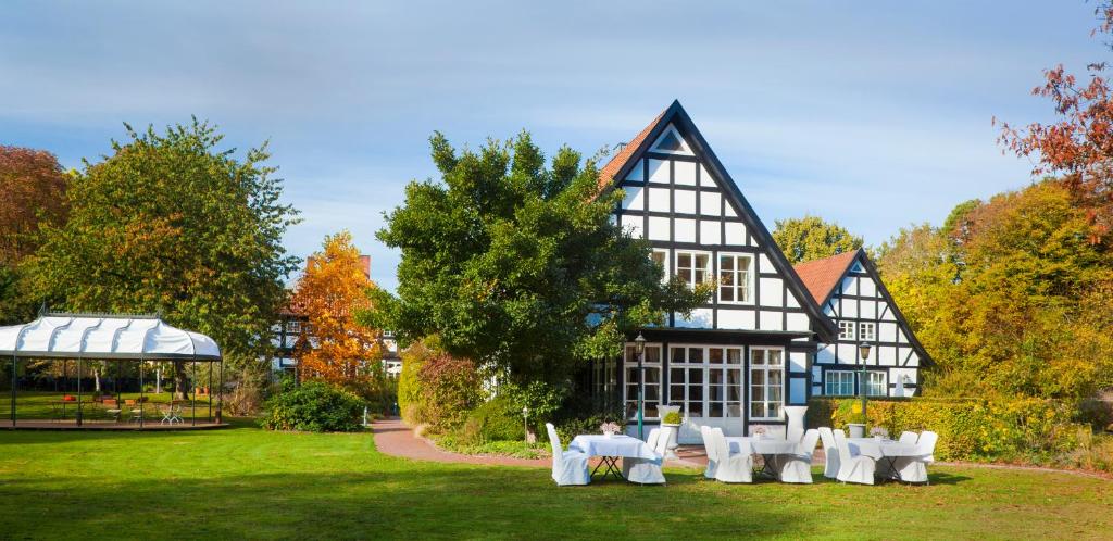 un grand bâtiment noir et blanc avec des tables et des chaises dans l'établissement Forsthaus Heiligenberg, à Bruchhausen-Vilsen