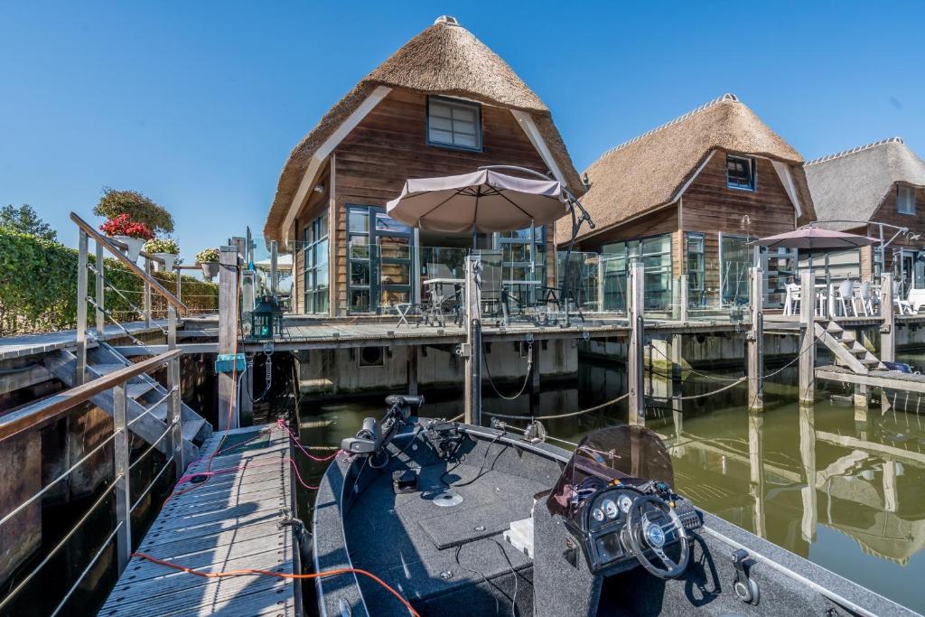 un barco atracado en un muelle con una casa en Nautic Rentals - Watervilla's Zuiderhoeve en De Heen