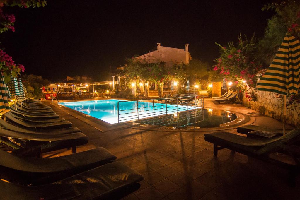 una piscina por la noche con sillas y luces en Meldi Hotel, en Kalkan