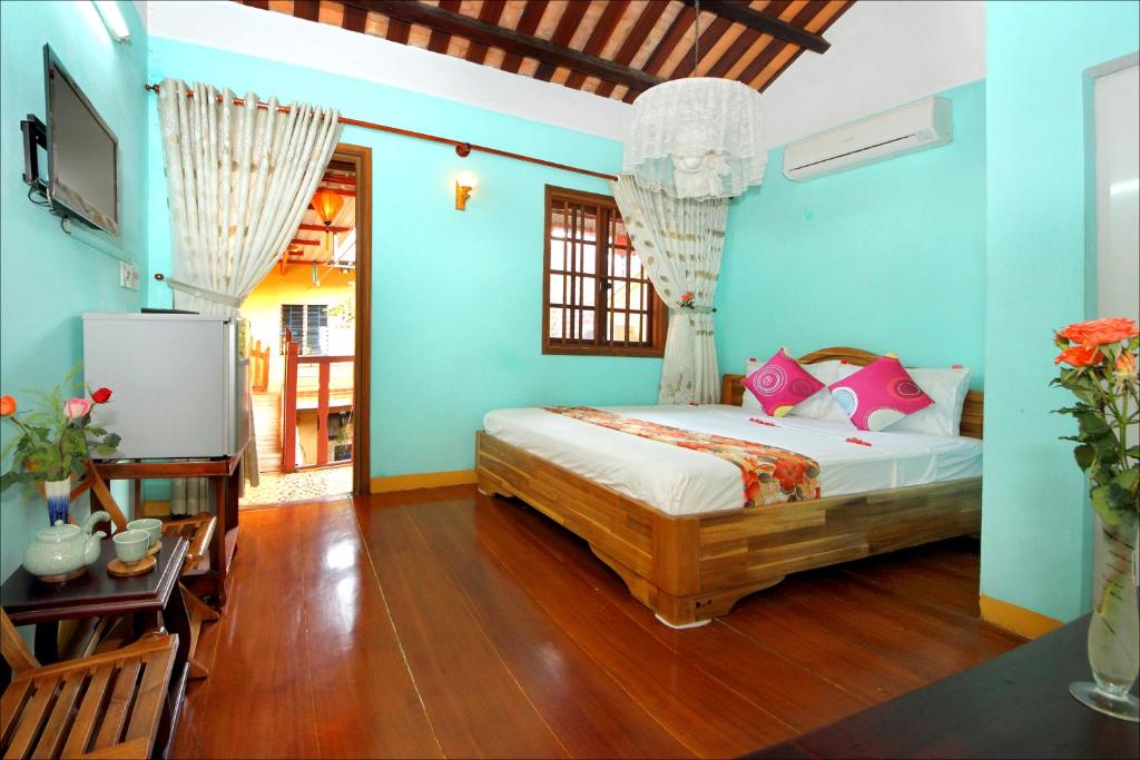 a bedroom with blue walls and a bed with pink pillows at Nha Lan Homestay in Hoi An