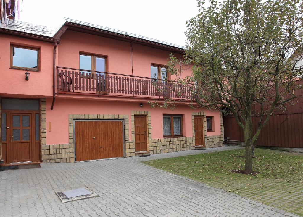 uma casa cor-de-rosa com uma varanda por cima em Penzión Antónia em Habovka