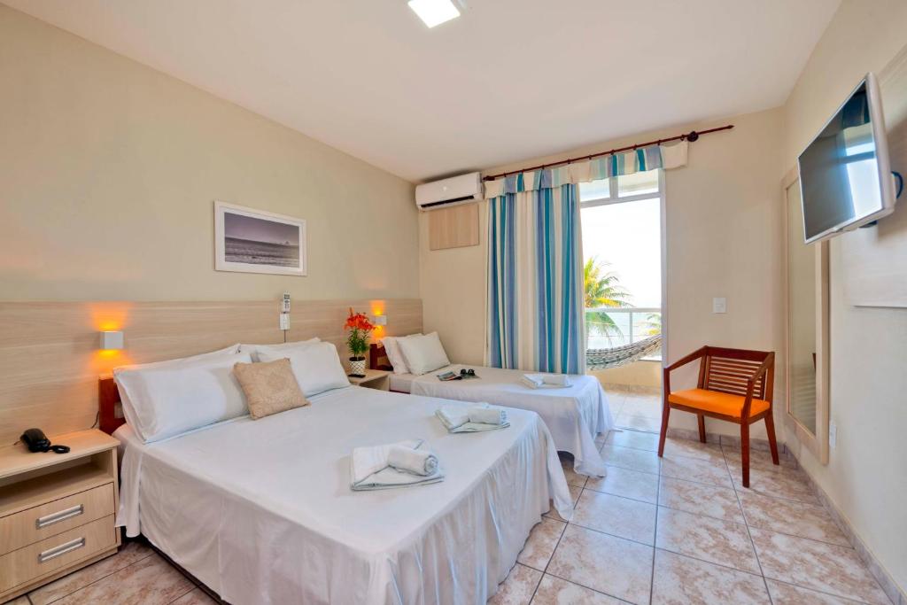a hotel room with two beds and a television at Hotel Portal da Lua in Iriri
