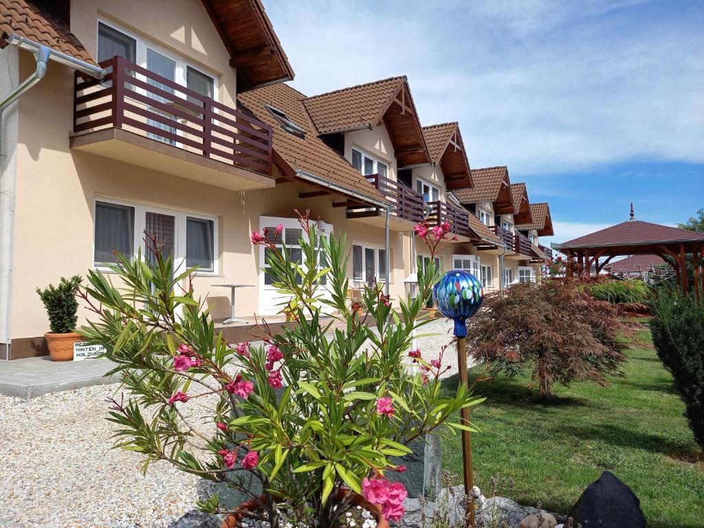 a row of houses with flowers in a yard at Petrovics Apartmanház in Bük