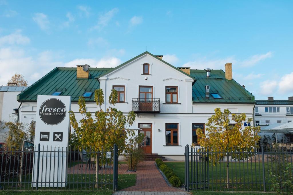 a white house with a green roof at Fresco Hostel in Suwałki