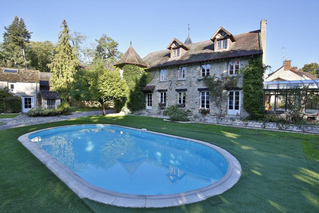Nainville-les-Roches的住宿－Le Clos Saint Lubin，房屋前方设有大型游泳池的庄园