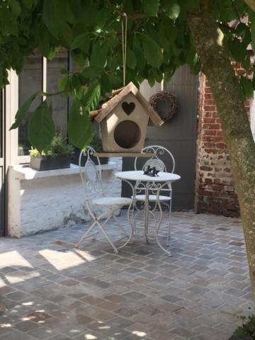 ein Vogelhaus, ein Stuhl und ein Tisch mit einem Vogelhaus in der Unterkunft Les Amandiers in Bouvigny-Boyeffles