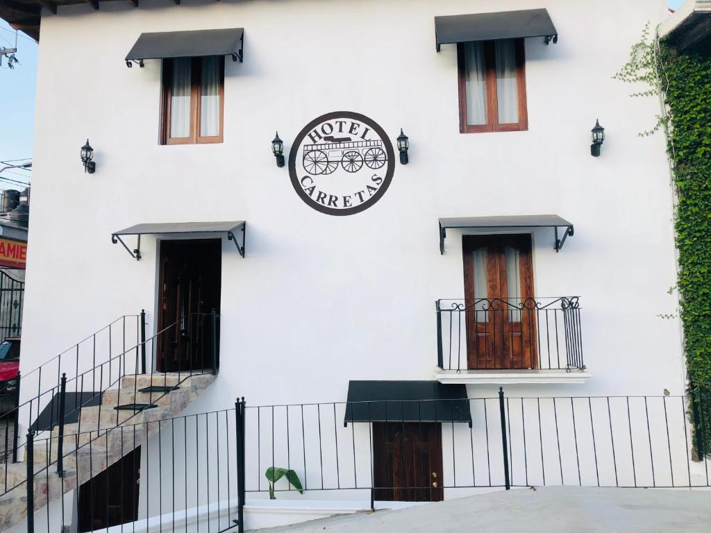 a white building with a clock on the side of it at Hotel Carretas by Rotamundos in Jalpan
