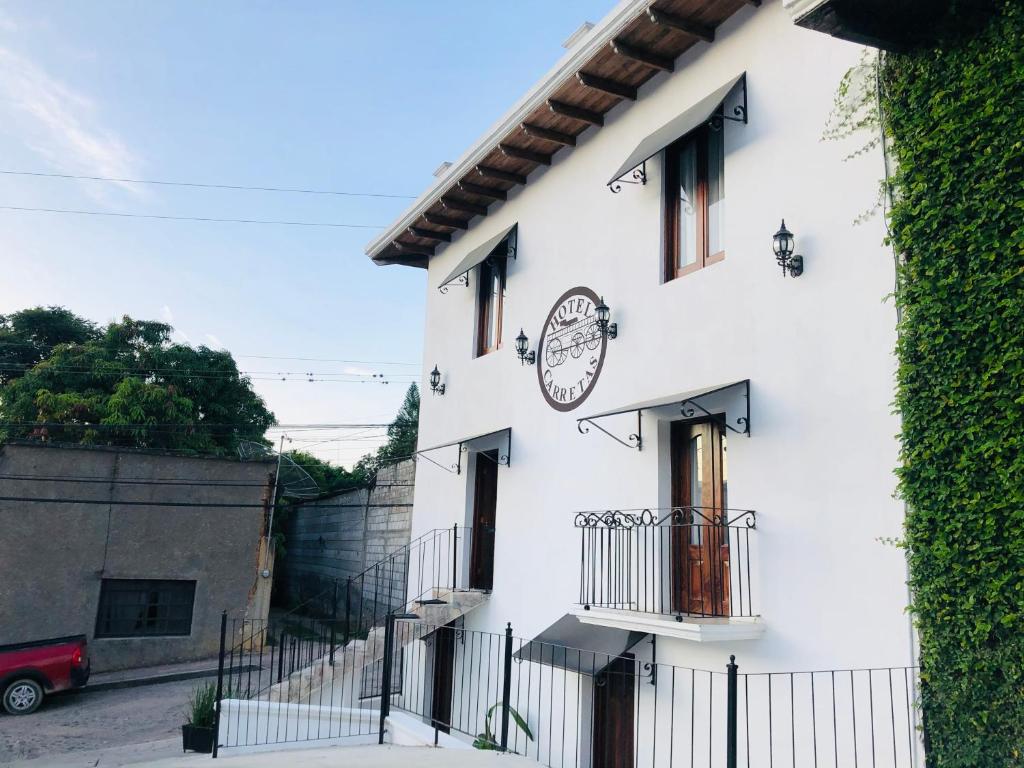 a white building with a clock on the side of it at Hotel Carretas by Rotamundos in Jalpan