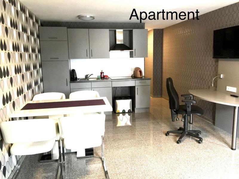 a kitchen with white chairs and a table and a counter at Hotel Mythos "Apartments" in Markgröningen