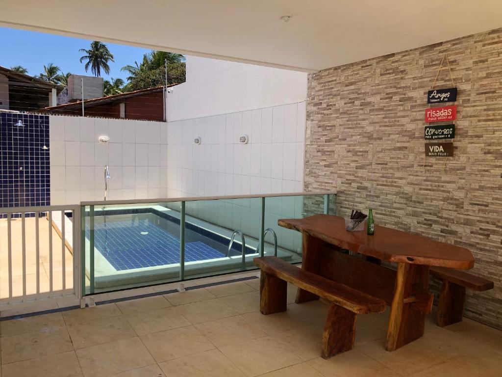 um quarto com um banco e uma piscina em Casa Conchas - Aluguel por Temporada Barra de São Miguel na Barra de São Miguel