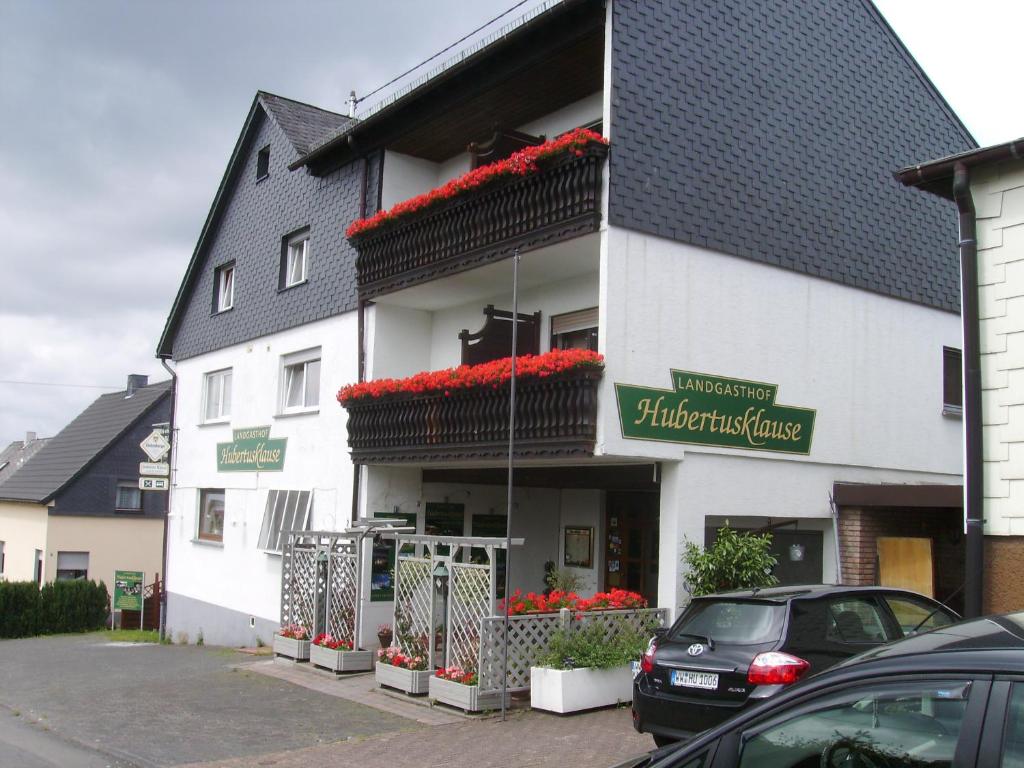 um edifício branco com flores vermelhas em frente em Landgasthaus Hubertusklause em Bad Marienberg