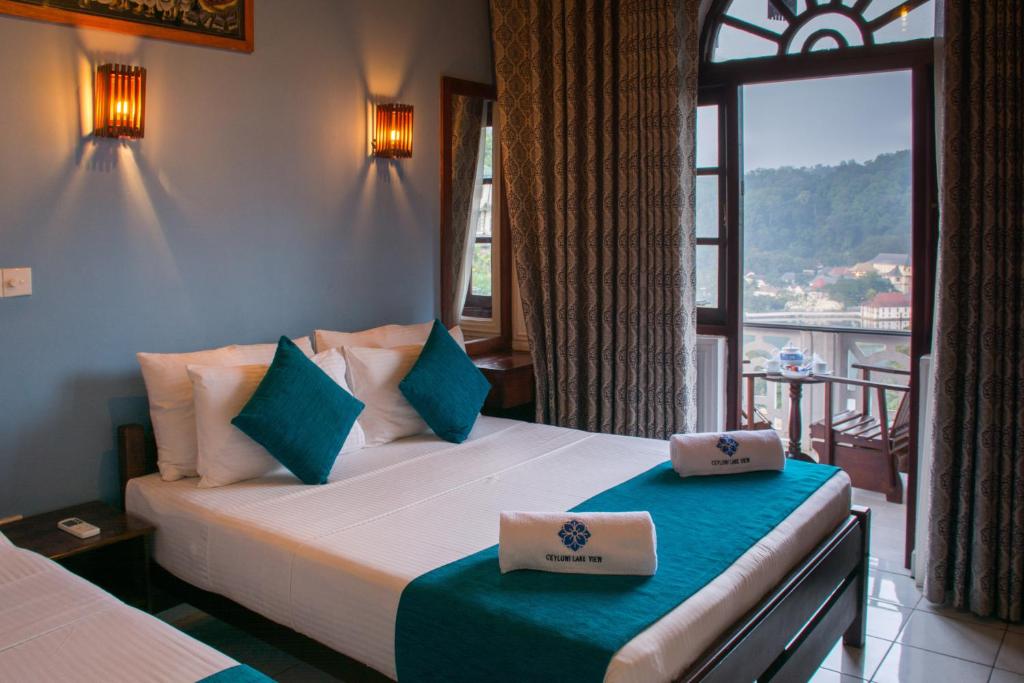 a bedroom with a bed and a window with a view at Ceyloni Lake Residency in Kandy