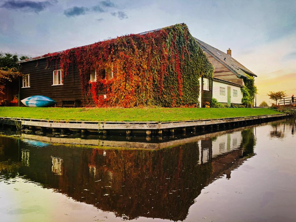 una casa con hiedra creciendo en ella junto a un río en Gieters Gruttertje, Vintage stay in the village centre, en Giethoorn