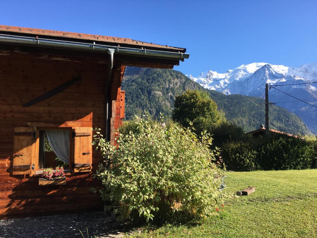 a log cabin with a window and mountains in the background at La Planque des Marmottes in Servoz