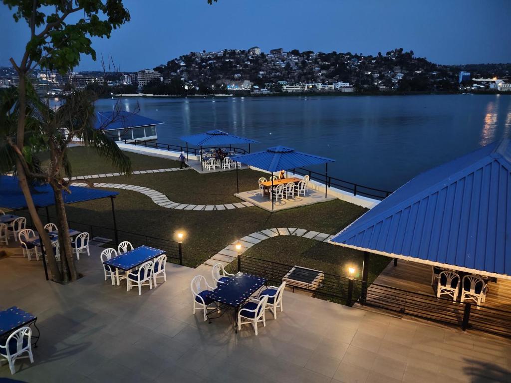 Blick auf eine Terrasse mit Tischen, Stühlen und Wasser in der Unterkunft Hotel Tilapia in Mwanza