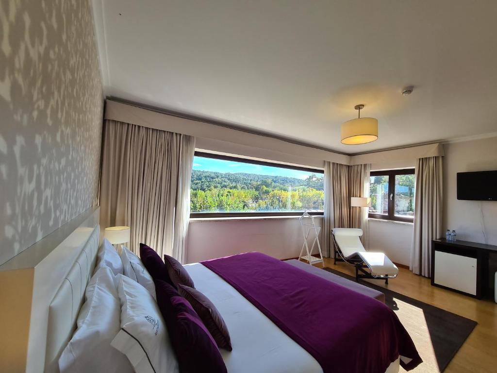 ein Schlafzimmer mit einem großen Bett und einem großen Fenster in der Unterkunft Quinta de Santo Estêvão Hotel Rural in Aguiar da Beira