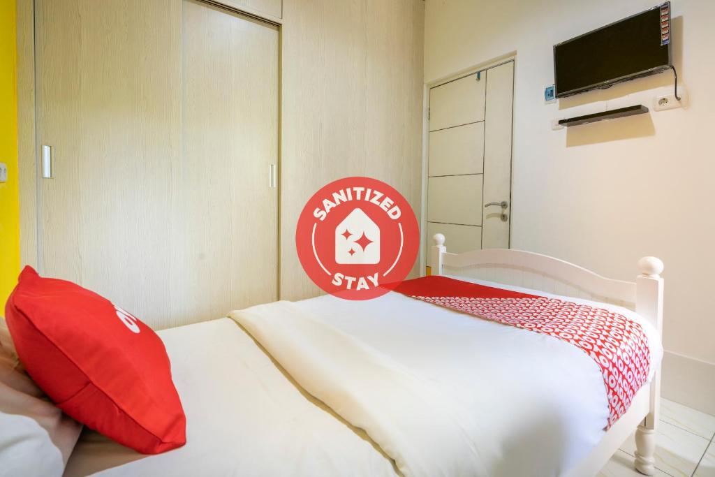 1 dormitorio con cama blanca y almohadas rojas en OYO 3782 Gunung Anyar en Surabaya