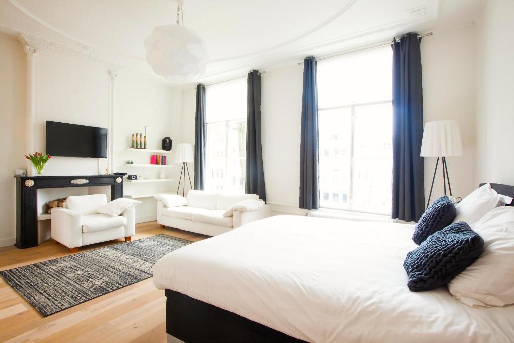 a white bedroom with a large bed and two chairs at Mokum Suites in Amsterdam