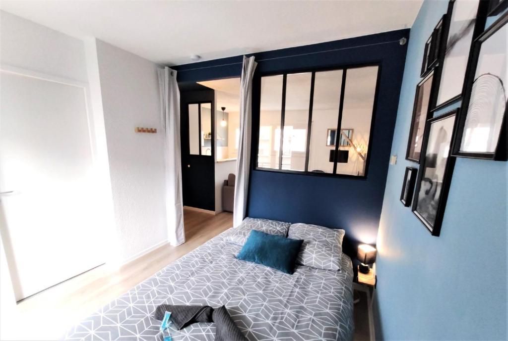 - une chambre avec un lit et un mur bleu dans l'établissement L'ÉGLANTINE - Proche Centre - Free Parking - Airbus, à Toulouse