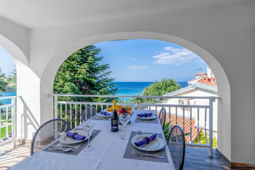 a table on a balcony with a view of the ocean at Maestral Apartments in Malinska