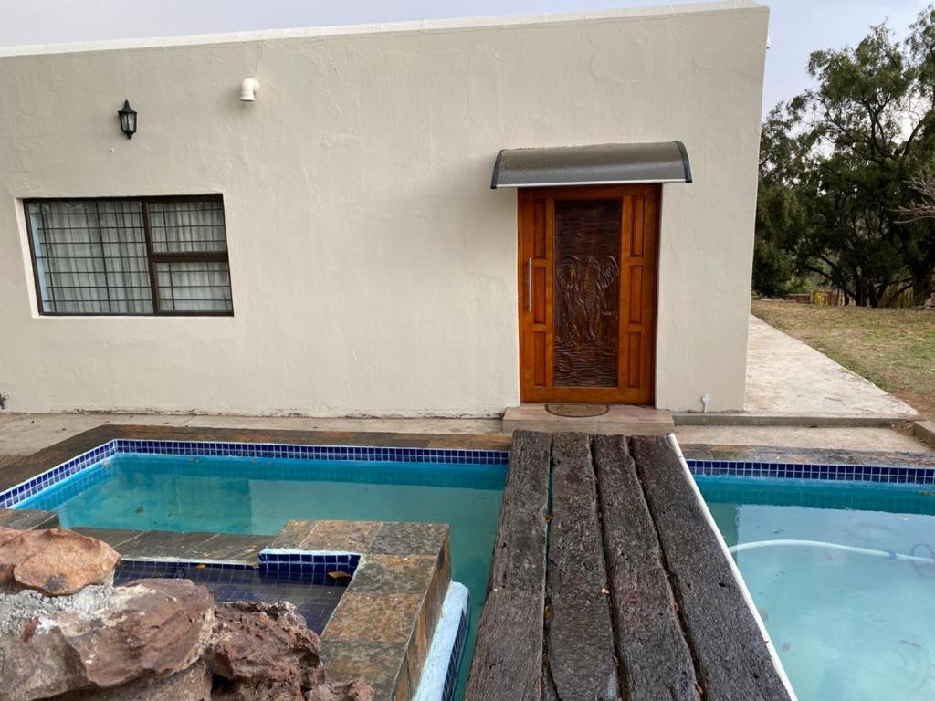 a house with a swimming pool in front of a house at JB Countrylife Accommodation in Koedoe