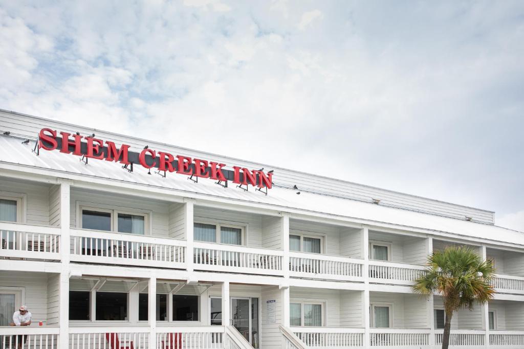 Un bâtiment blanc avec un panneau en haut dans l'établissement Shem Creek Inn, à Charleston